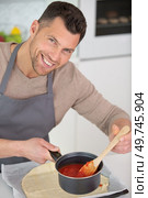 man in kitchen cooking with sauce pan looking at camera. Стоковое фото, агентство Ingram Publishing / Фотобанк Лори
