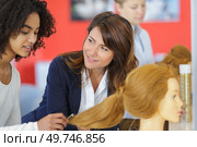 female hairdresser learning with a hair on dummy. Стоковое фото, агентство Ingram Publishing / Фотобанк Лори