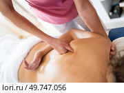 High angle of anonymous osteopathic therapist massaging using fist on shoulder bone at back of patient lying face down during physiotherapy session in modern clinic. Crop female osteopathic therapist massaging back of patient. Стоковое фото, агентство Ingram Publishing / Фотобанк Лори
