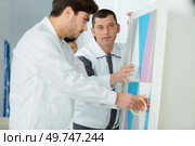 trainee painter using masking tape before painting. Стоковое фото, агентство Ingram Publishing / Фотобанк Лори
