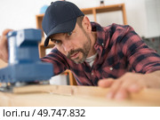 man sanding wood with electric sander polisher. Стоковое фото, агентство Ingram Publishing / Фотобанк Лори