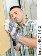 Builder fitting insulation into framework on wall. Стоковое фото, агентство Ingram Publishing / Фотобанк Лори