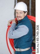cheerful builder carrying red pipe. Стоковое фото, агентство Ingram Publishing / Фотобанк Лори