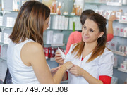 young female pharmacist putting cream on clients hands. Стоковое фото, агентство Ingram Publishing / Фотобанк Лори
