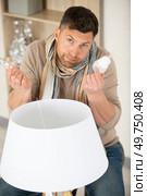 mature doesnt know which bulb to fit in his lamp. Стоковое фото, агентство Ingram Publishing / Фотобанк Лори