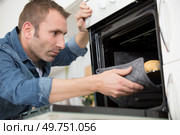 man taking baked loafs of bread out of the oven. Стоковое фото, агентство Ingram Publishing / Фотобанк Лори