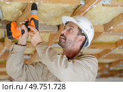 builder using cordless drill on wooden ceiling joist. Стоковое фото, агентство Ingram Publishing / Фотобанк Лори