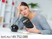unhappy woman with calculator and piggy bank. Стоковое фото, агентство Ingram Publishing / Фотобанк Лори
