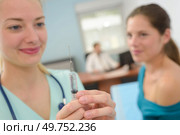 Nurse preparing syringe for female patient. Стоковое фото, агентство Ingram Publishing / Фотобанк Лори