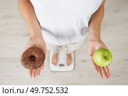 woman on bathroom scales holding an apple and a donut. Стоковое фото, агентство Ingram Publishing / Фотобанк Лори