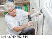 Handyman caulking a window frame. Стоковое фото, агентство Ingram Publishing / Фотобанк Лори