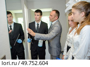 Trainee cleaning a mirror under supervision. Стоковое фото, агентство Ingram Publishing / Фотобанк Лори