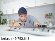 Young man fitting kitchen hob. Стоковое фото, агентство Ingram Publishing / Фотобанк Лори