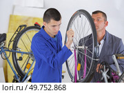 trainee mechanic working on bicycle under supervision. Стоковое фото, агентство Ingram Publishing / Фотобанк Лори