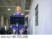 Blonde fit young caucasian woman exercising using elliptical machine in the gym. Woman exercising using elliptical machine in the gym. Стоковое фото, агентство Ingram Publishing / Фотобанк Лори