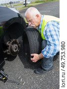 aged man changing leaking tire on the verge. Стоковое фото, агентство Ingram Publishing / Фотобанк Лори