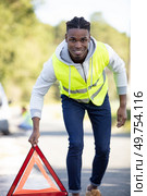 young man placing warning side on road after breakdown. Стоковое фото, агентство Ingram Publishing / Фотобанк Лори