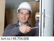 builder is using a screwdriver to adjust a door hinge. Стоковое фото, агентство Ingram Publishing / Фотобанк Лори