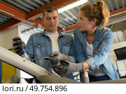 woman questioning male colleague in garage as he works. Стоковое фото, агентство Ingram Publishing / Фотобанк Лори