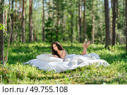 Young woman is reading a book in the forest lying on a mattress. The girl relaxing in nature. Стоковое фото, агентство Ingram Publishing / Фотобанк Лори