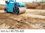 A compact roller is actively compressing dirt on a construction site, where the ground has recently been excavated. Стоковое фото, фотограф Виктория Тельминова / Фотобанк Лори