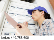 woman electrician inspecting fuseboard holding clipboard. Стоковое фото, агентство Ingram Publishing / Фотобанк Лори