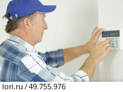 installing a programmable room thermostat. Стоковое фото, агентство Ingram Publishing / Фотобанк Лори