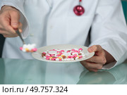 Medic holding tablets forward on a spoon. Стоковое фото, агентство Ingram Publishing / Фотобанк Лори