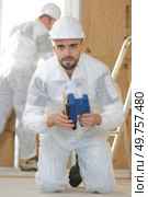 portrait of worker kneeling on floor holding sander. Стоковое фото, агентство Ingram Publishing / Фотобанк Лори