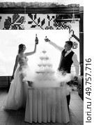 newlyweds at a banquet pour champagne into a pile of glasses for guests. Стоковое фото, агентство Ingram Publishing / Фотобанк Лори