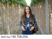 A cheerful and vibrant young woman is joyfully posing in a picturesque vineyard, showcasing her stylish and fashionable outfit amidst the beautiful and lush rows of grapevines that surround her. A Young Woman Smiling Happily in a Vineyard Surrounded by Beautiful Lush Green Rows. Стоковое фото, агентство Ingram Publishing / Фотобанк Лори