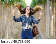 In a picturesque vineyard, a cheerful young woman playfully flips her hair, highlighting her stylish outfit while surrounded by vibrant and lush greenery that adds to the beauty of the scene. A Joyful Young Woman with Flowing Hair Strolling Along a Picturesque Path in a Vineyard. Стоковое фото, агентство Ingram Publishing / Фотобанк Лори