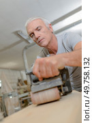 Senior carpenter using a belt sander. Стоковое фото, агентство Ingram Publishing / Фотобанк Лори