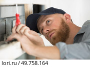 young male builder using screwdriver on wooden joist. Стоковое фото, агентство Ingram Publishing / Фотобанк Лори