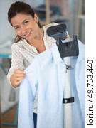 woman using a vertical steam for clothes. Стоковое фото, агентство Ingram Publishing / Фотобанк Лори