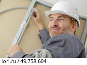 tradesman putting up cable trunking. Стоковое фото, агентство Ingram Publishing / Фотобанк Лори