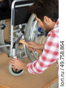 man is repairing a wheelchair at workshop. Стоковое фото, агентство Ingram Publishing / Фотобанк Лори