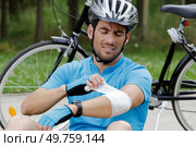 male cyclist wrapping his injured elbow. Стоковое фото, агентство Ingram Publishing / Фотобанк Лори