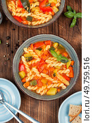 Bowl of minestrone soup with fresh vegetables and pasta, rustic background. Rustic style. Italian minestrone soup on wooden background. Стоковое фото, агентство Ingram Publishing / Фотобанк Лори