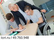 teacher helping a disable student at class. Стоковое фото, агентство Ingram Publishing / Фотобанк Лори