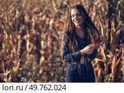 A joyful and carefree young woman is playfully and happily touching her beautiful hair while standing in the middle of a golden cornfield, perfectly capturing the essence and beauty of autumn. A Young Woman With a Bright Smile Enjoying the Splendor of a Beautiful Cornfield in Autumn. Стоковое фото, агентство Ingram Publishing / Фотобанк Лори