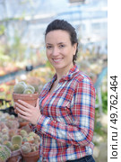 portrait of woman in garden center holding cactus plant. Стоковое фото, агентство Ingram Publishing / Фотобанк Лори