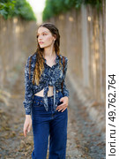 A stylish and fashionable young woman poses gracefully and elegantly amidst a serene and peaceful vinecovered pathway, showcasing her trendy and chic outfit with confidence and poise. A stylish model gracefully poses in nature, surrounded by a beautiful botanical backdrop. Стоковое фото, агентство Ingram Publishing / Фотобанк Лори