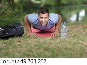 happy man doing push upson grass in summer. Стоковое фото, агентство Ingram Publishing / Фотобанк Лори