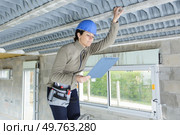 female construction worker on a stepladder with clipboard inspecting roof. Стоковое фото, агентство Ingram Publishing / Фотобанк Лори