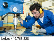 serious trainees focused on drilling metal piece with professional machinery. Стоковое фото, агентство Ingram Publishing / Фотобанк Лори