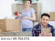 man looking at frames while pregnant wife taping the boxes. Стоковое фото, агентство Ingram Publishing / Фотобанк Лори