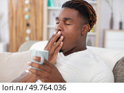 tired man sitting on sofa yawning. Стоковое фото, агентство Ingram Publishing / Фотобанк Лори