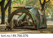 A tent is pitched in the center of a park, surrounded by grass and trees under a clear sky.. Tent Set Up in Park. Стоковое фото, агентство Ingram Publishing / Фотобанк Лори