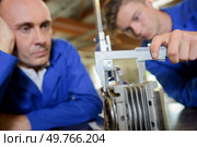 Apprentice measuring a cylinder with a vernier guage. Стоковое фото, агентство Ingram Publishing / Фотобанк Лори